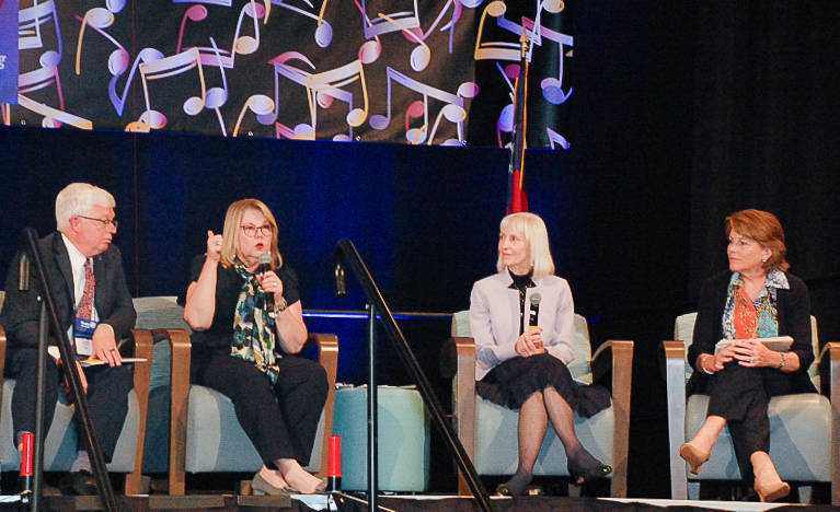 Four adults in chairs on a stage for a panel discussion about mental health.