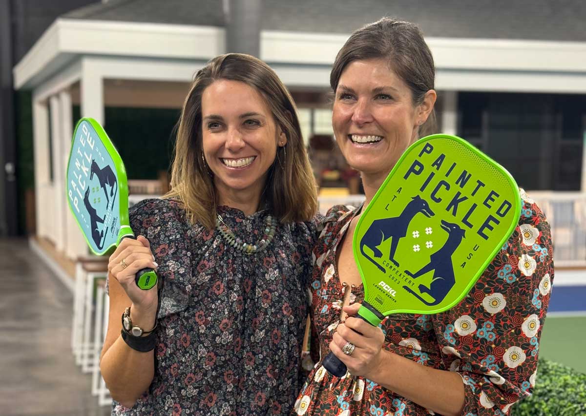 two women holding pickleball raquets and smiling: Christie Farmer and Elizabeth Waller, 2024 Skyland Slam chairs