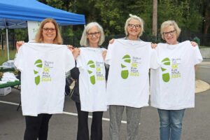 four women hold up 2024 Skyland Trail 5K Run/Walk tshirts and smile