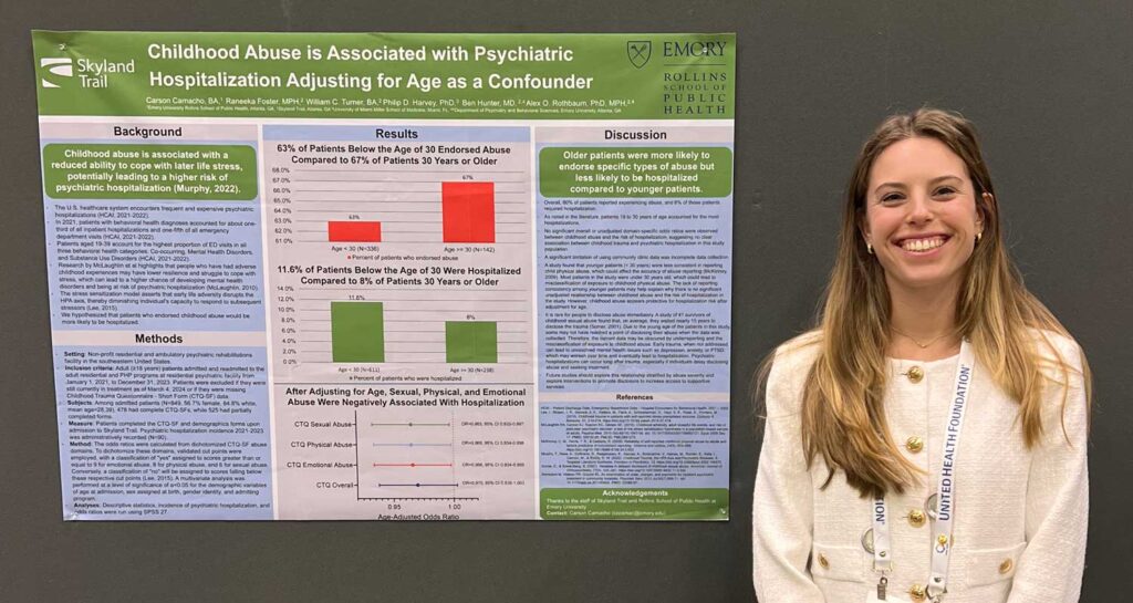 Young woman stands in front of research poster on childhood traum and mental health