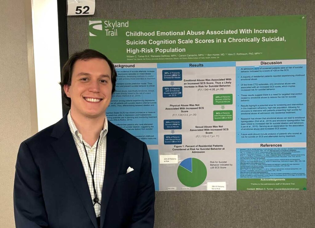 Young man standing in front of research poster on trauma and mental health