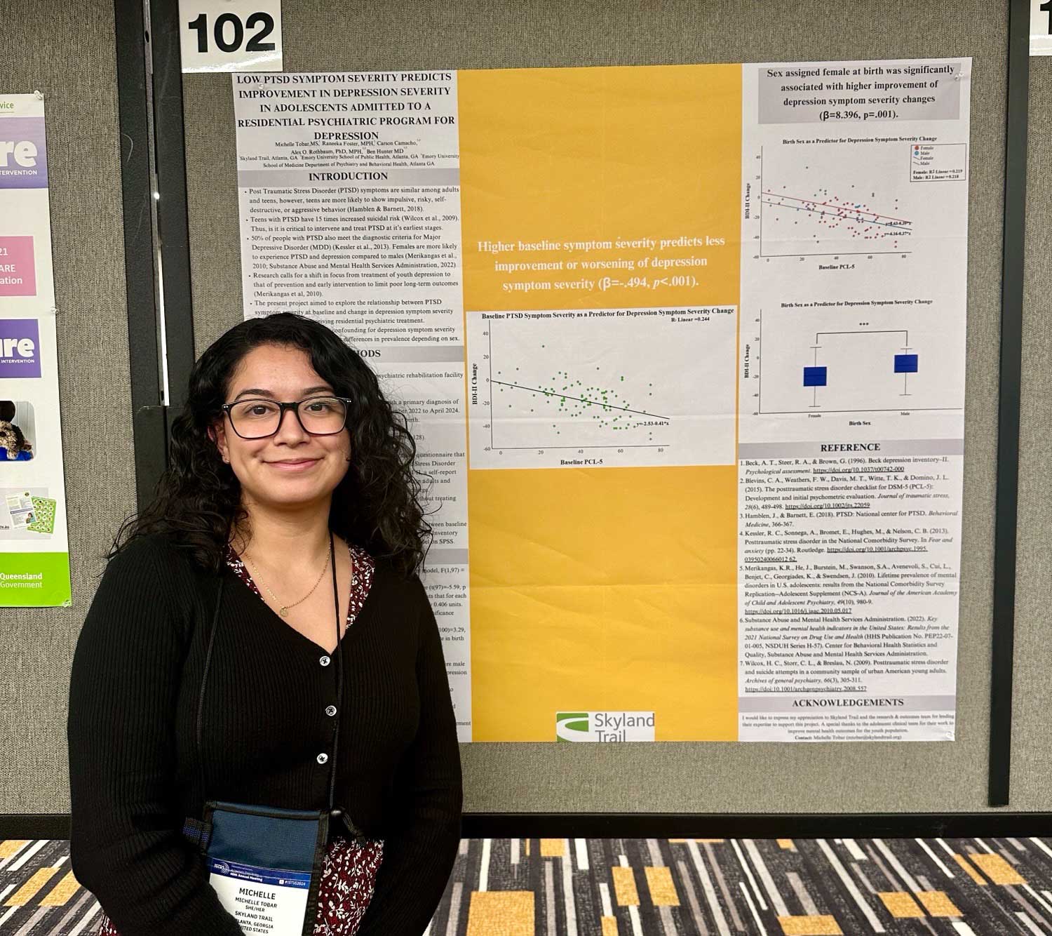 Young woman stands in front of research poster