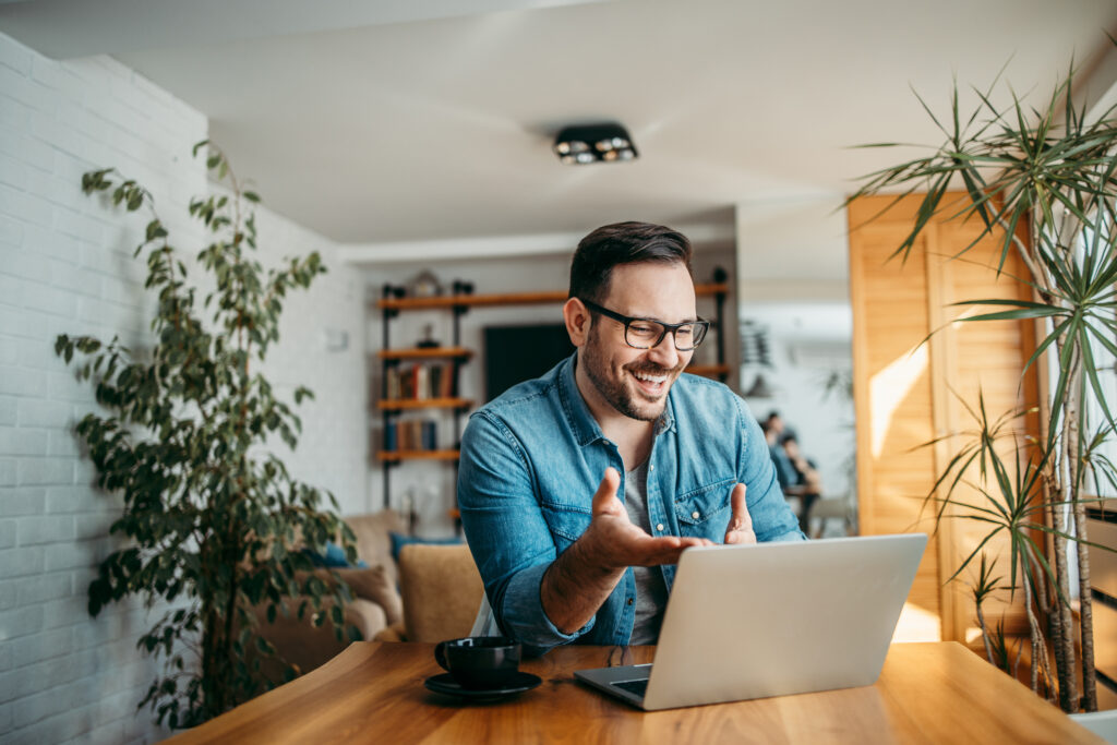 Portrait of a cheerful man having video call on laptop computer.