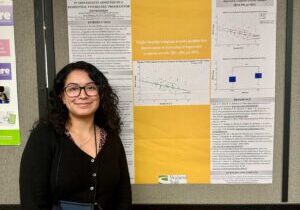 Young woman stands in front of research poster