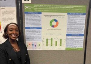 Young woman stands in front of research poster