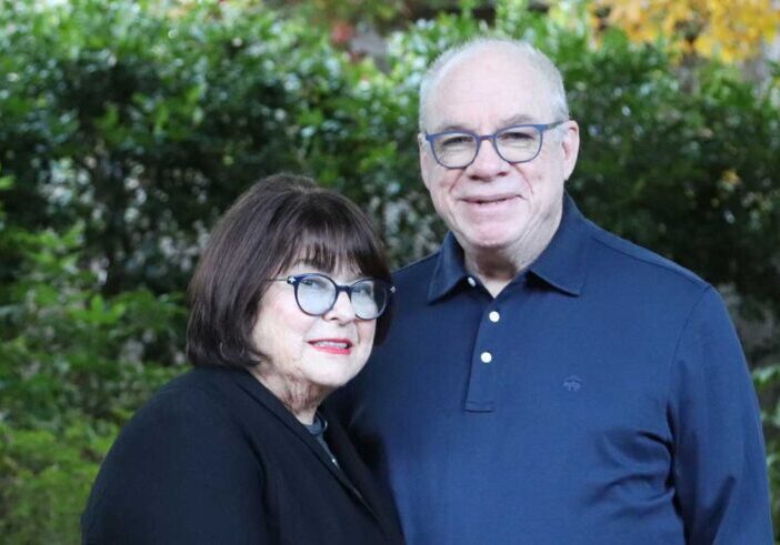 a wife and husband stand smiling